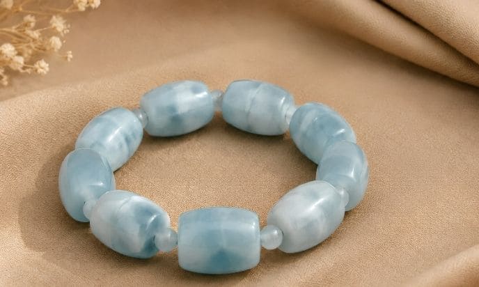 Handcrafted aquamarine barrel bead bracelet on elegant beige fabric backdrop