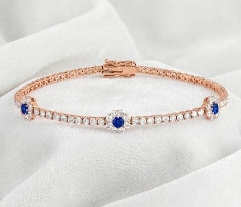 Rose gold sapphire and diamond bracelet featuring centered floral cluster design on white satin background