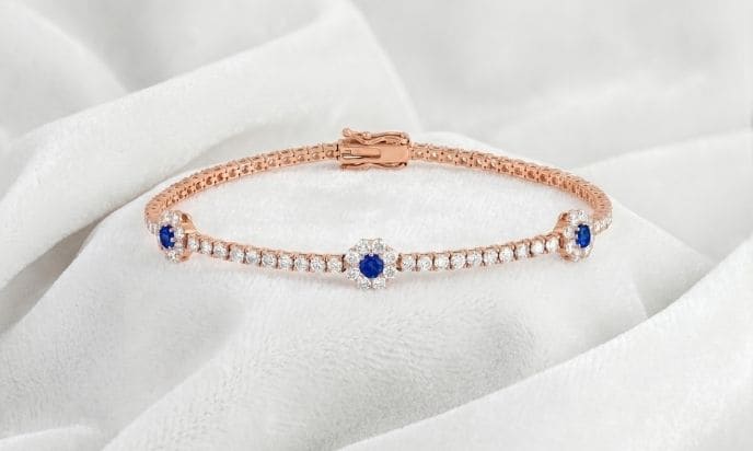 Rose gold sapphire and diamond bracelet featuring centered floral cluster design on white satin background