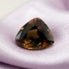 Natural trillion-cut earthfire andalusite loose gemstone on elegant satin fabric
