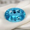 Brilliant oval electric blue apatite loose gemstone displayed on luxury satin fabric