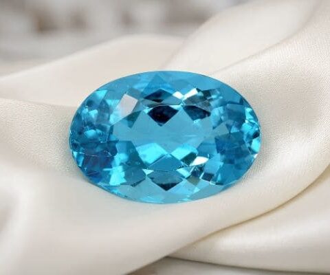 Brilliant oval electric blue apatite loose gemstone displayed on luxury satin fabric