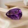 Elegant pear-cut violet amethyst loose gemstone on luxurious satin fabric