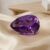 Elegant pear-cut violet amethyst loose gemstone on luxurious satin fabric