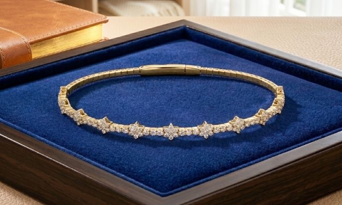 Yellow gold flexible beaded flower cluster bangle with natural diamond floral accents displayed in luxury jewelry box
