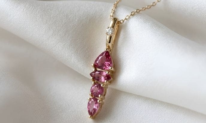 Pink tourmaline gold pendant necklace on white satin