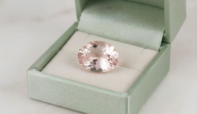 Natural oval soft pink morganite loose gemstone displayed on elegant satin fabric