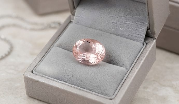 Premium oval soft pink morganite loose gemstone showcased on luxurious white satin fabric
