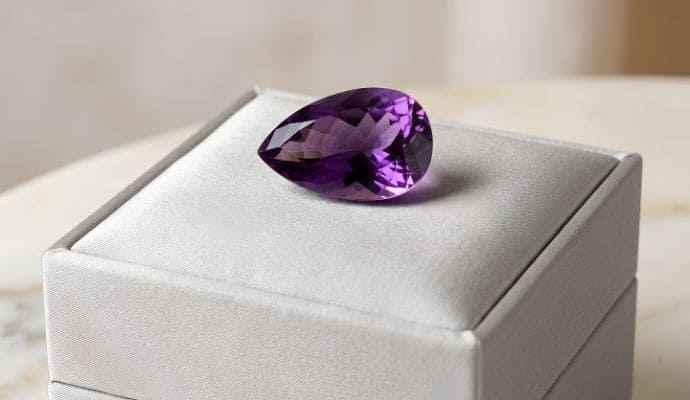Natural pear-cut violet amethyst loose gemstone on elegant white jewelry display