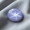 Natural blue gray star sapphire gemstone on soft grey fabric
