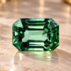 Natural emerald cut blue green sapphire gemstone on warm stone surface