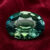 Natural oval blue green sapphire gemstone on red velvet fabric
