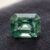 Natural emerald cut blue green sapphire gemstone on dark fabric