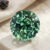 Natural round blue green sapphire gemstone on light stone surface