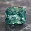 Natural blue green sapphire gemstone on dark stone surface