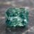 Natural blue green sapphire gemstone on dark stone surface