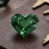 Natural heart shaped blue green sapphire gemstone on brown jewelry surface