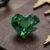 Natural heart shaped blue green sapphire gemstone on brown jewelry surface