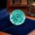 Natural round blue green tourmaline gemstone on navy jewelry display
