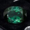 Natural oval blue green tourmaline gemstone on black jewelry display