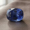 Natural blue sapphire gemstone with GIA report showing cushion cut and deep blue brilliance