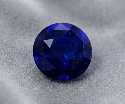 Natural round blue sapphire gemstone on soft grey fabric