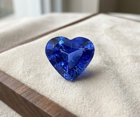 Natural heart shaped blue sapphire gemstone on cream jewelry display