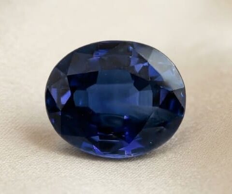 Natural oval blue sapphire gemstone on soft beige fabric