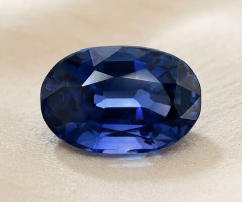 Natural oval blue sapphire gemstone on soft beige fabric
