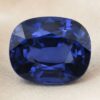 Natural cushion cut blue sapphire gemstone on soft beige fabric