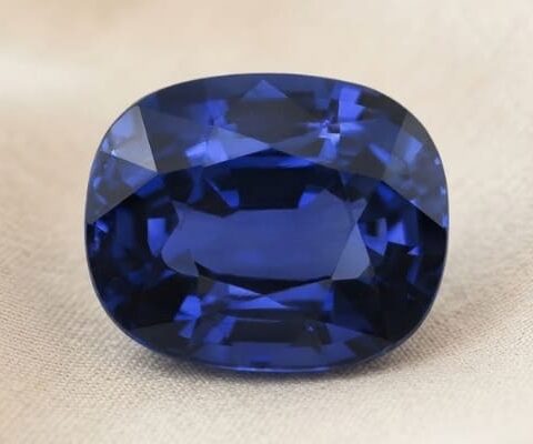 Natural cushion cut blue sapphire gemstone on soft beige fabric