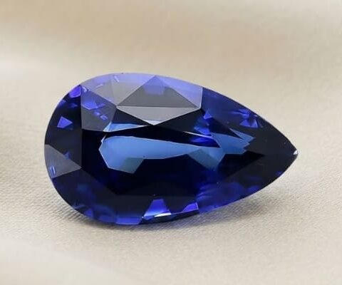 Natural pear shaped blue sapphire with GIA report on soft cream fabric