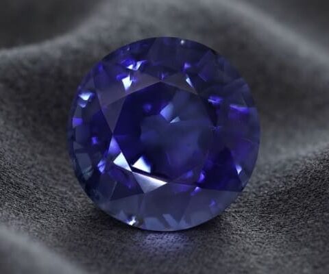 Natural round blue sapphire gemstone on dark grey fabric