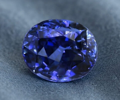 Natural oval blue sapphire with GIA report on dark grey fabric