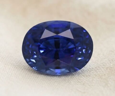 Natural oval blue sapphire gemstone on soft cream fabric