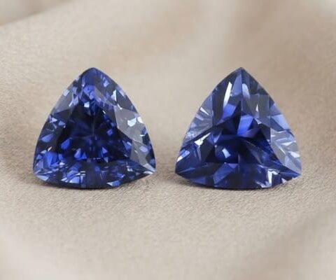 Natural trillion cut blue sapphire matching pair on soft beige fabric