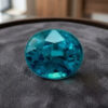 Natural round blue zircon gemstone on dark grey jewelry display