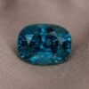 Natural cushion cut blue zircon gemstone on soft brown fabric