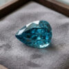 Natural pear shaped blue zircon gemstone on grey jewelry display tray