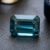Natural emerald cut blue zircon gemstone on dark jewelry display