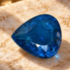 Natural blue Paraiba tourmaline gemstone on warm textured surface