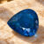 Natural blue Paraiba tourmaline gemstone on warm textured surface