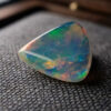 Natural triangular Brazilian opal gemstone on dark textured fabric
