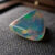 Natural triangular Brazilian opal gemstone on dark textured fabric