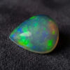 Natural pear shaped Brazilian opal gemstone on dark textured fabric