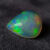 Natural pear shaped Brazilian opal gemstone on dark textured fabric