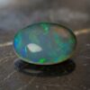 Natural oval Brazilian opal gemstone on dark stone surface
