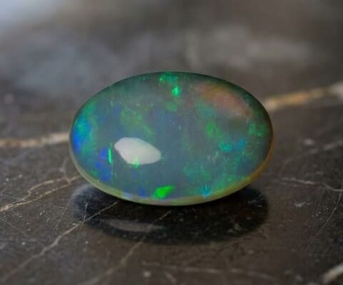 Natural oval Brazilian opal gemstone on dark stone surface