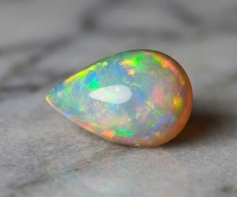 Natural pear shaped Brazilian opal gemstone on light stone surface
