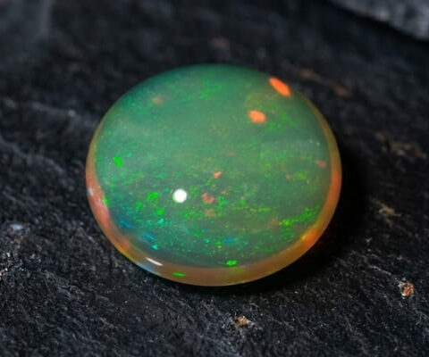 Natural Brazilian opal gemstone on dark stone surface